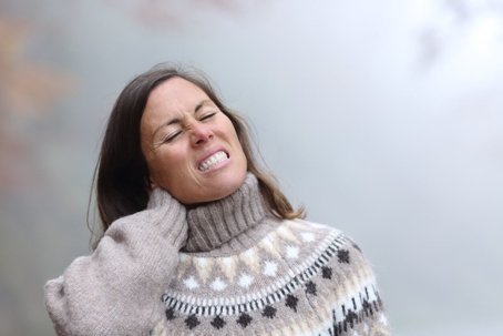 Middle age woman suffering neck ache in winter.