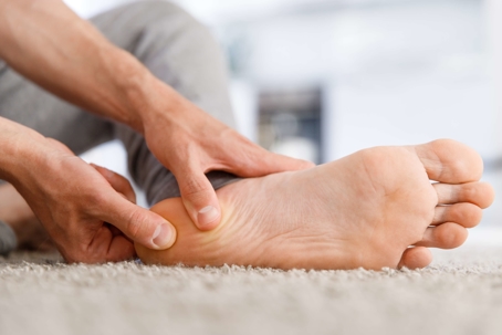 Man is massaging his foot to relieve pain