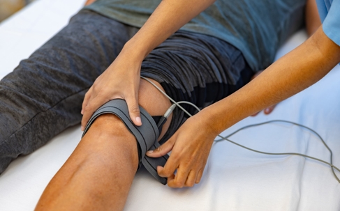 Man in physical therapy getting electrical stimulation on his knee
